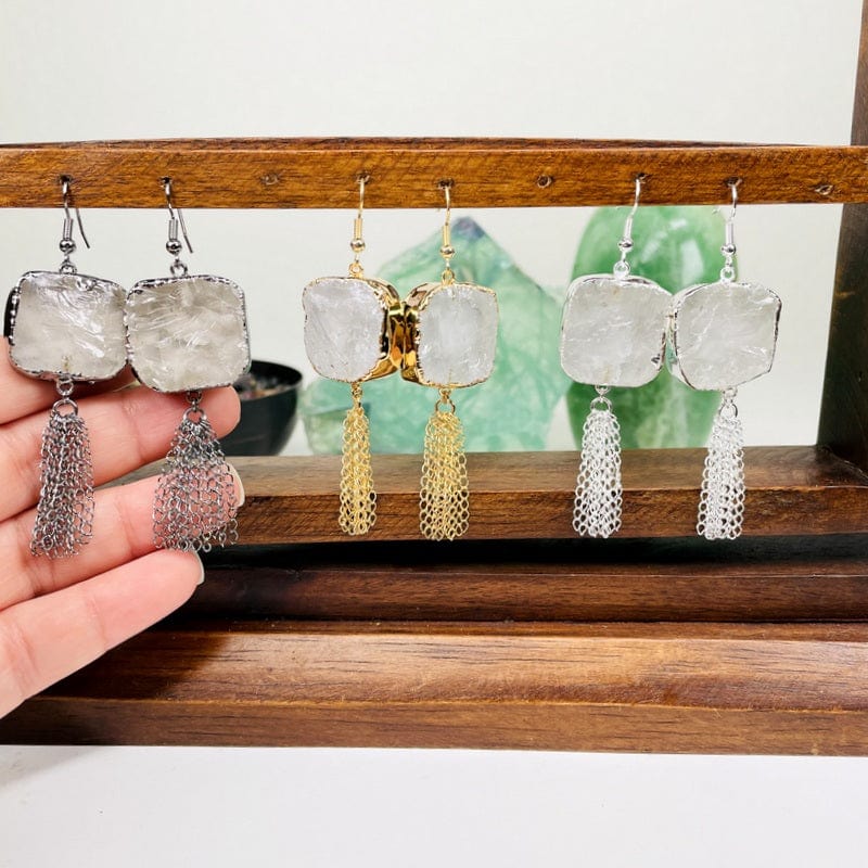 crystal quartz earrings with chain tassels in hand for size reference 