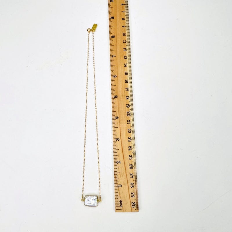 necklace next to a ruler for size reference 
