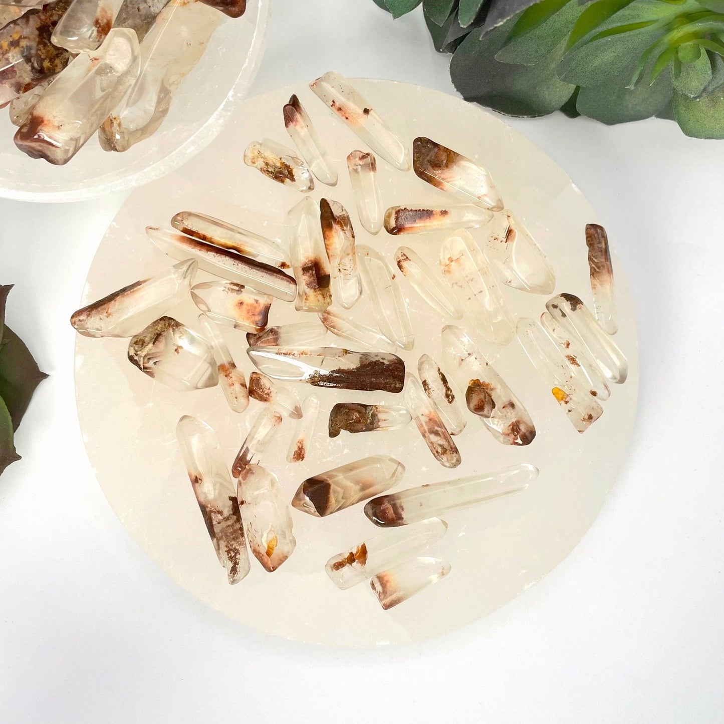 many small tumbled quartz with hematite points on display for possible variations
