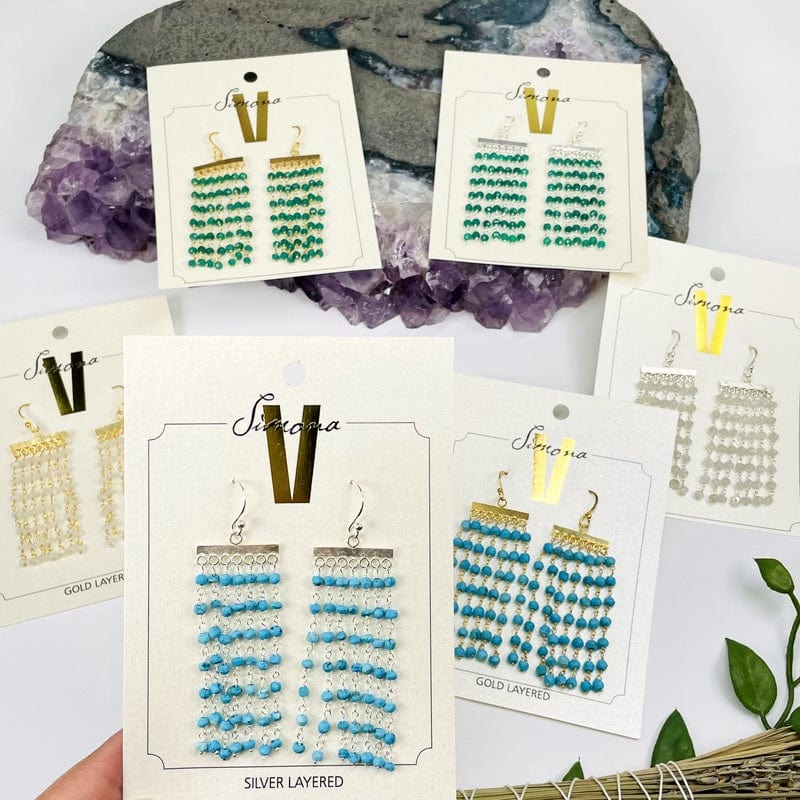6 different gemstone cascade earrings with decorations in the background