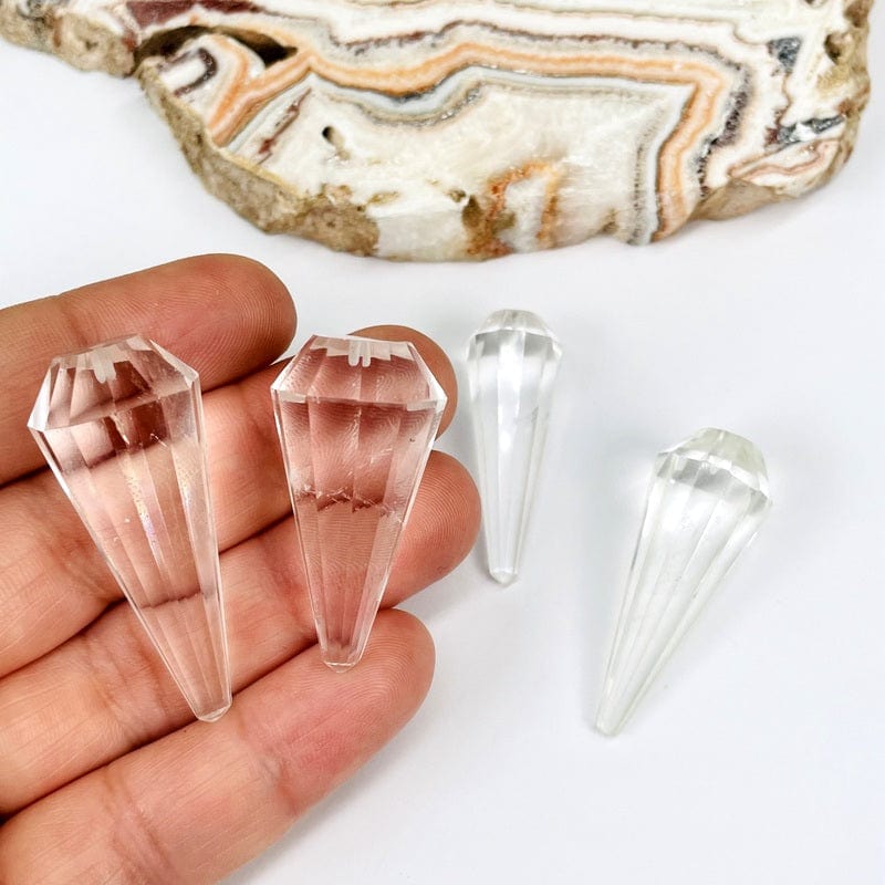 crystal quartz pendulum points in hand for size reference 