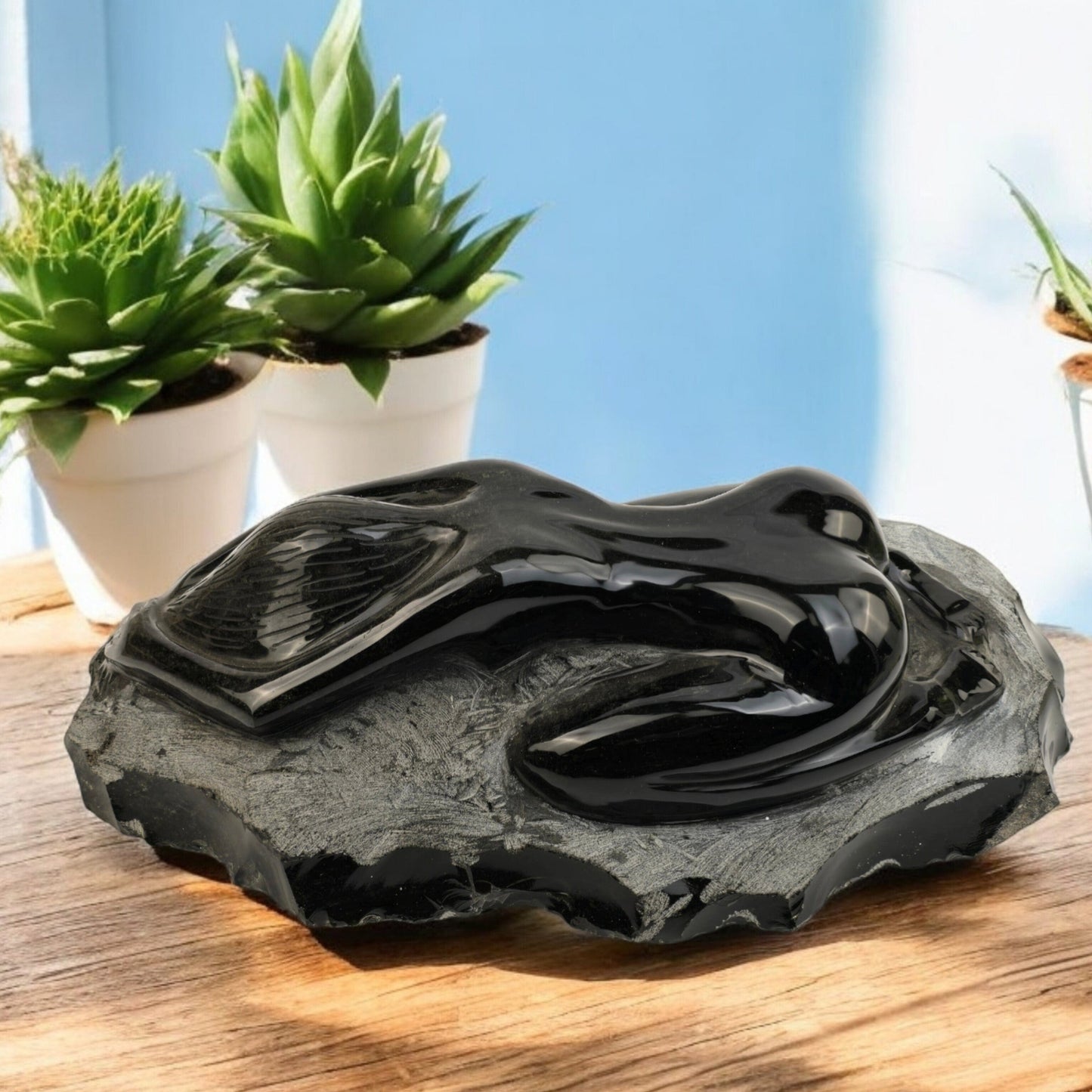 Silver Sheen Obsidian Yoga Goddess Crystal Sculpture - Child's Pose - One-of-a-Kind on wooden table with plants in the background
