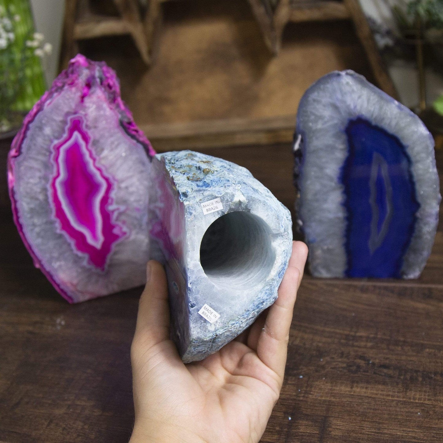 One agate lamp in a hand showing the opening of the lamp. Two agate lamps in the background.