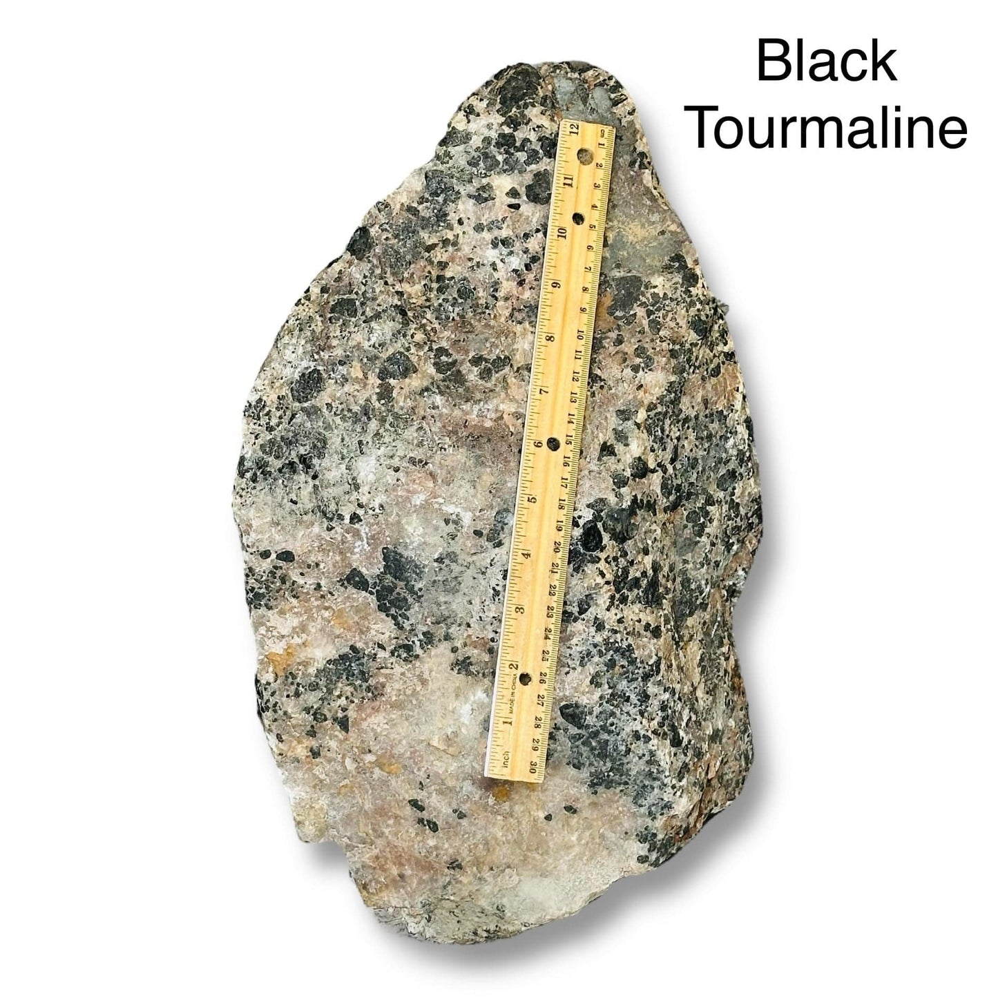 large rough stone crystal next to a ruler for size reference 