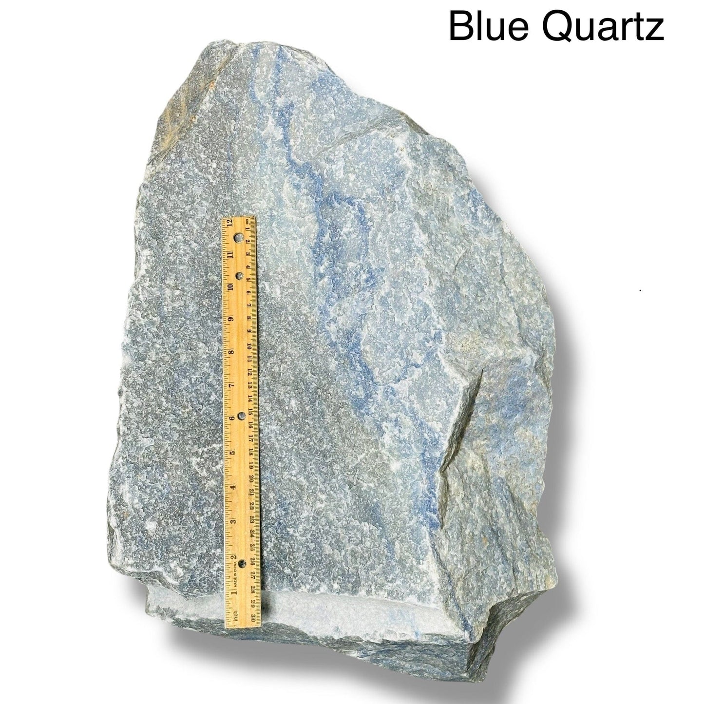large rough stone crystal next to a ruler for size reference 