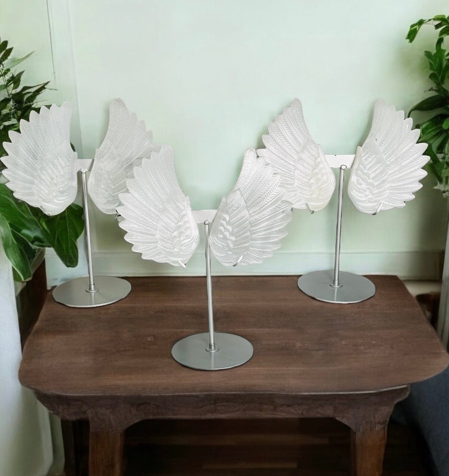 multiple selenite wings on metal stand displayed next to each other to shot the slight differences in the sizes and color shades