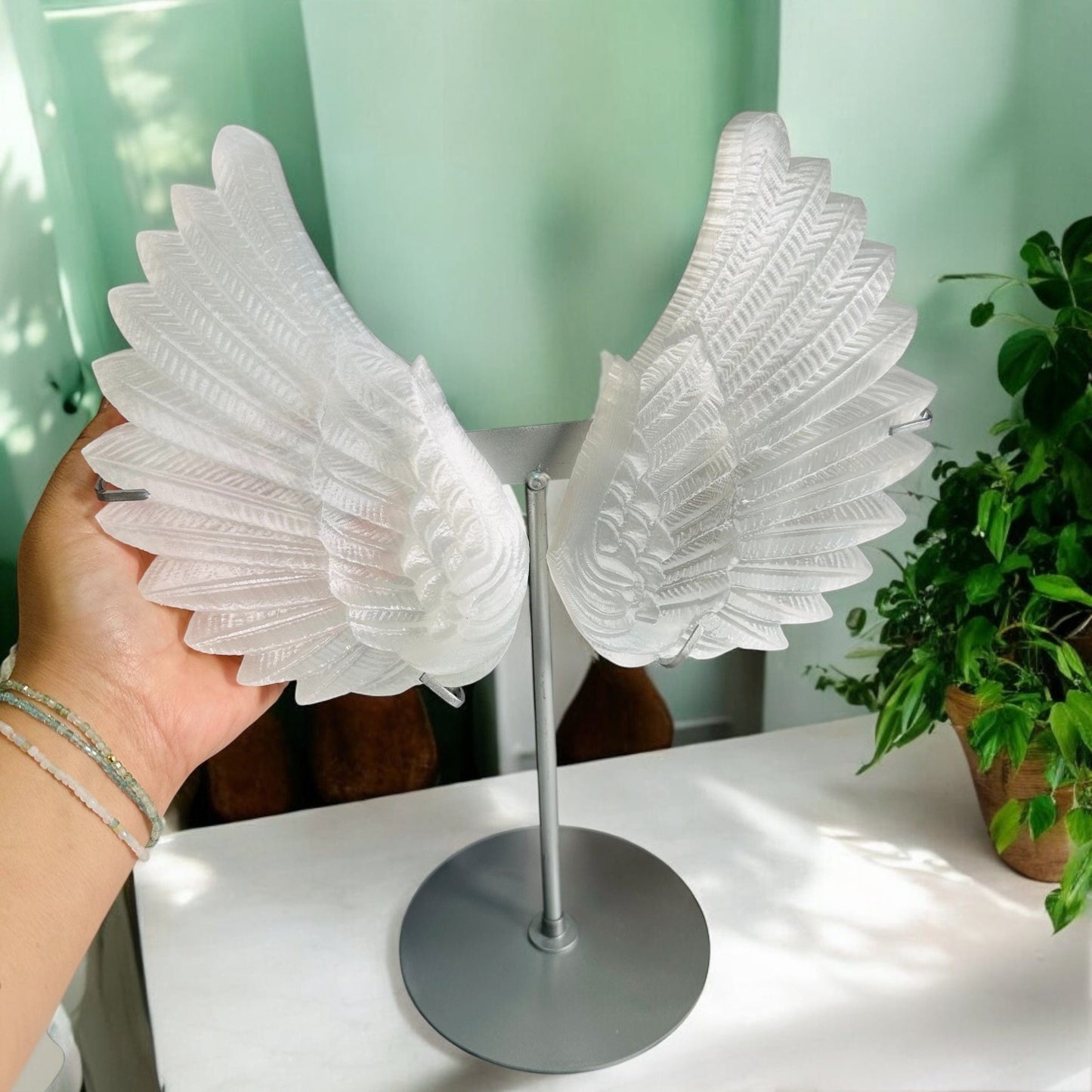 selenite angel wings next to hand for size reference 