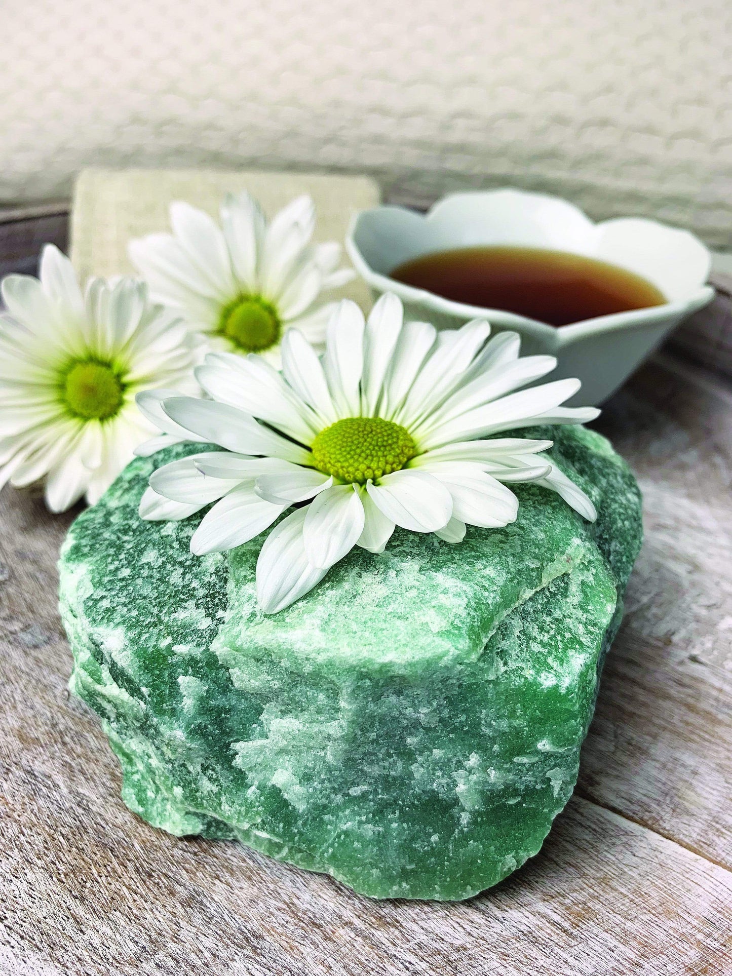 green quartz candle holder on display in front of backdrop with a flower in the candle holder hole