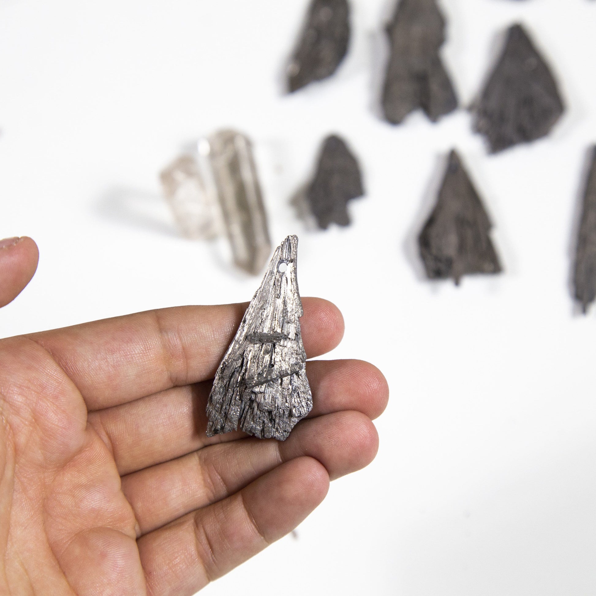 hand holding up platinum titanium treated blade with others blurred in the background