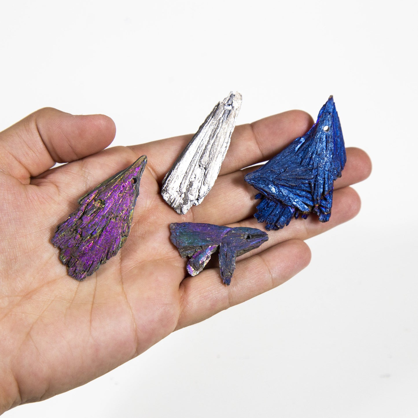 hand holding different types of titanium treated kyanite blades onw hwite background