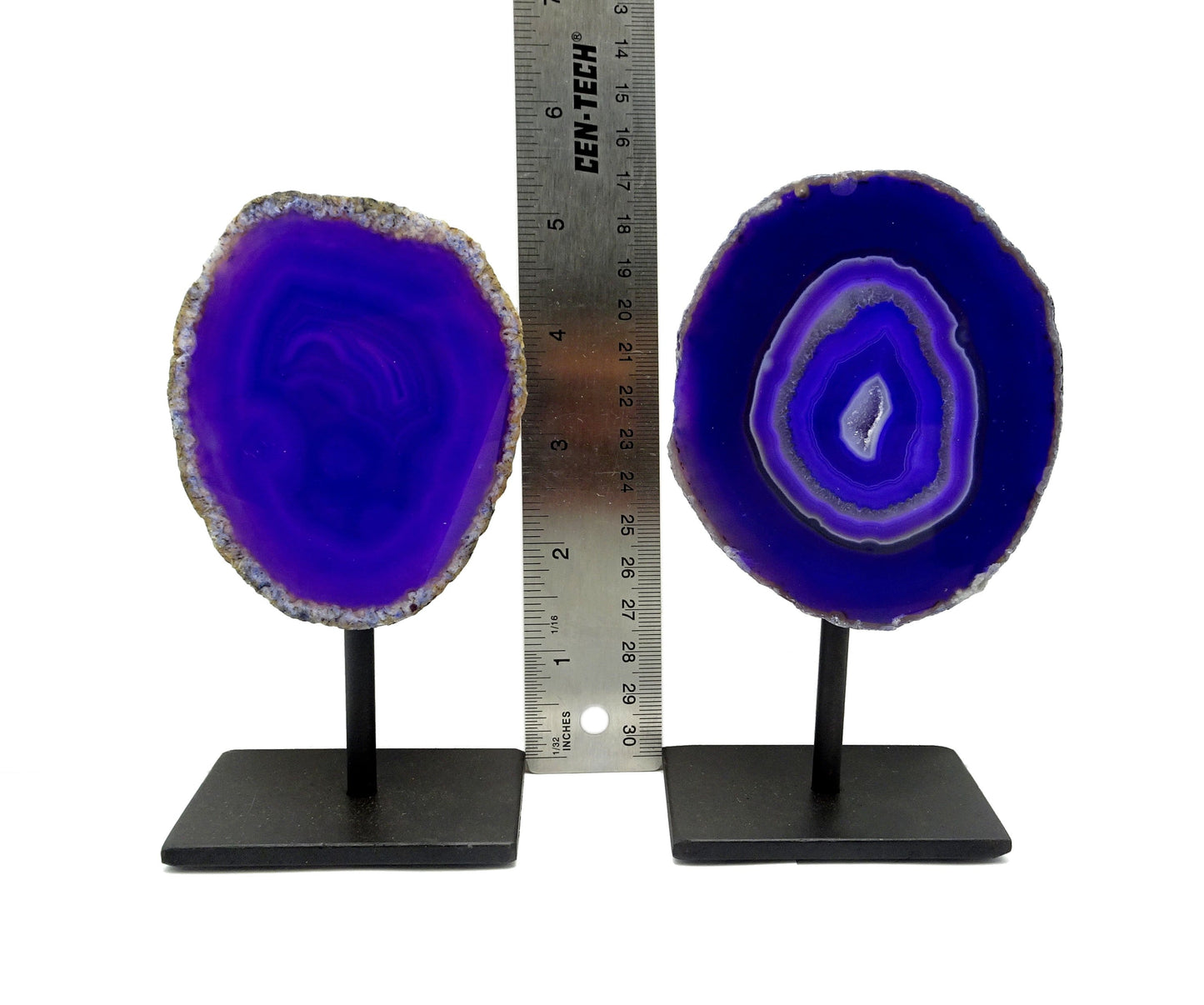 Two front facing agate geodes on a metal base next to a ruler for size reference.