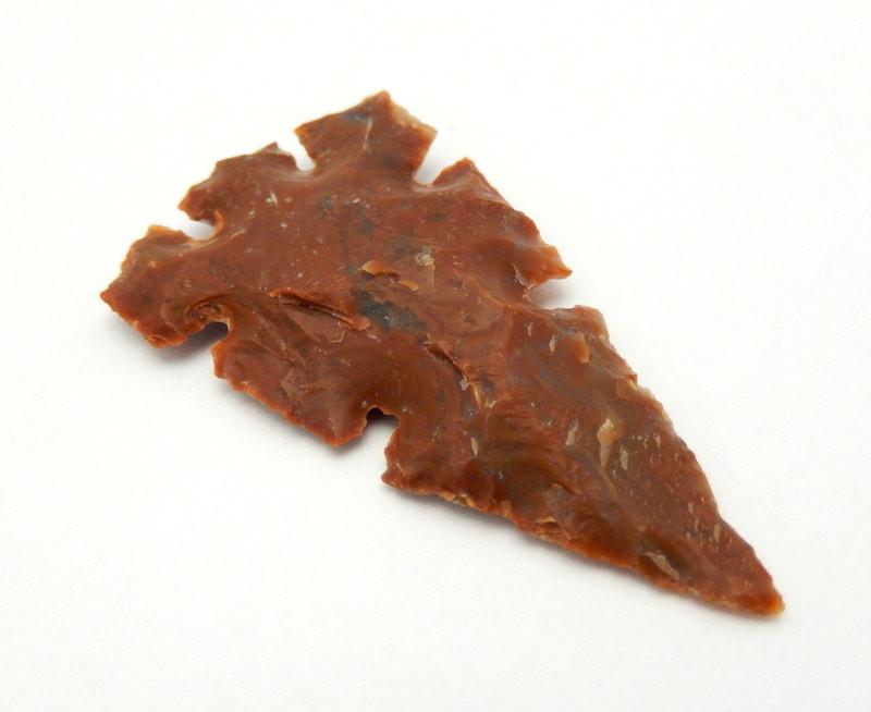 close up side angle of one carved jasper arrowhead on a white background