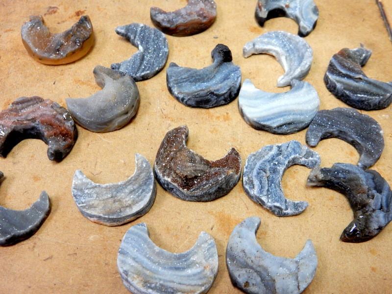 Group of Raw Chalcedony Moon Crescents scattered on tan background