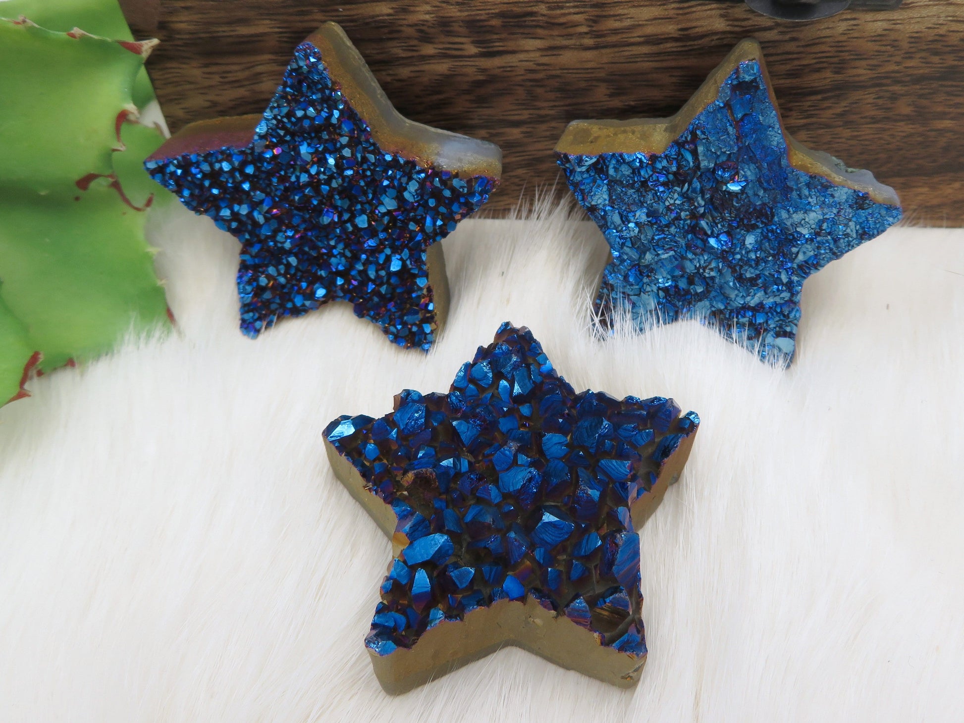 Three Mystic Blue Titanium Treated Druzy Stars displayed on fuzzy white surface.