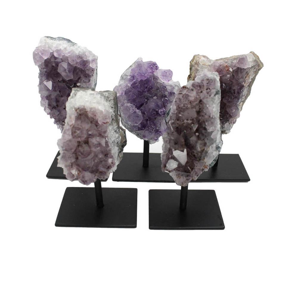 5 assorted amethyst clusters on a black metal base on a white background.