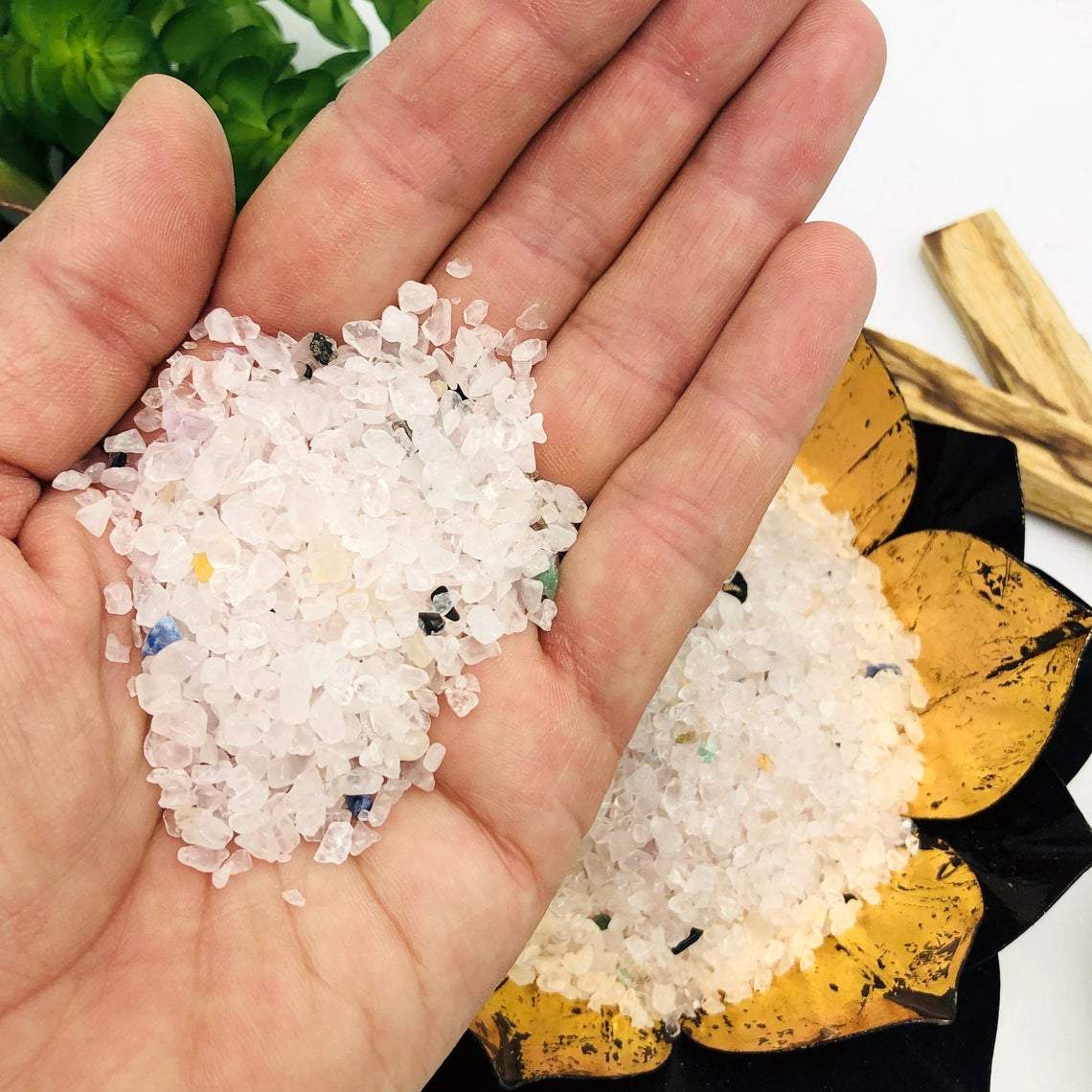 hand holding up pile of Rose Quartz Tiny Chip Stones with more in the background