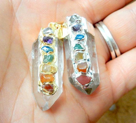 hand holding up 2 Crystal Quartz Point Pendants in gold and silver