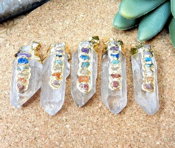5 gold Crystal Quartz Point Pendants on brown background