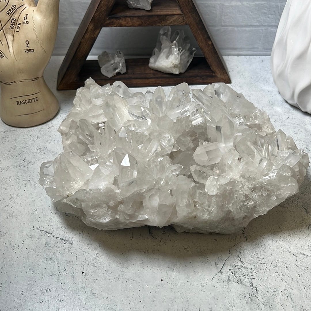 Large crystal cluster with points all over it on a cement background.
