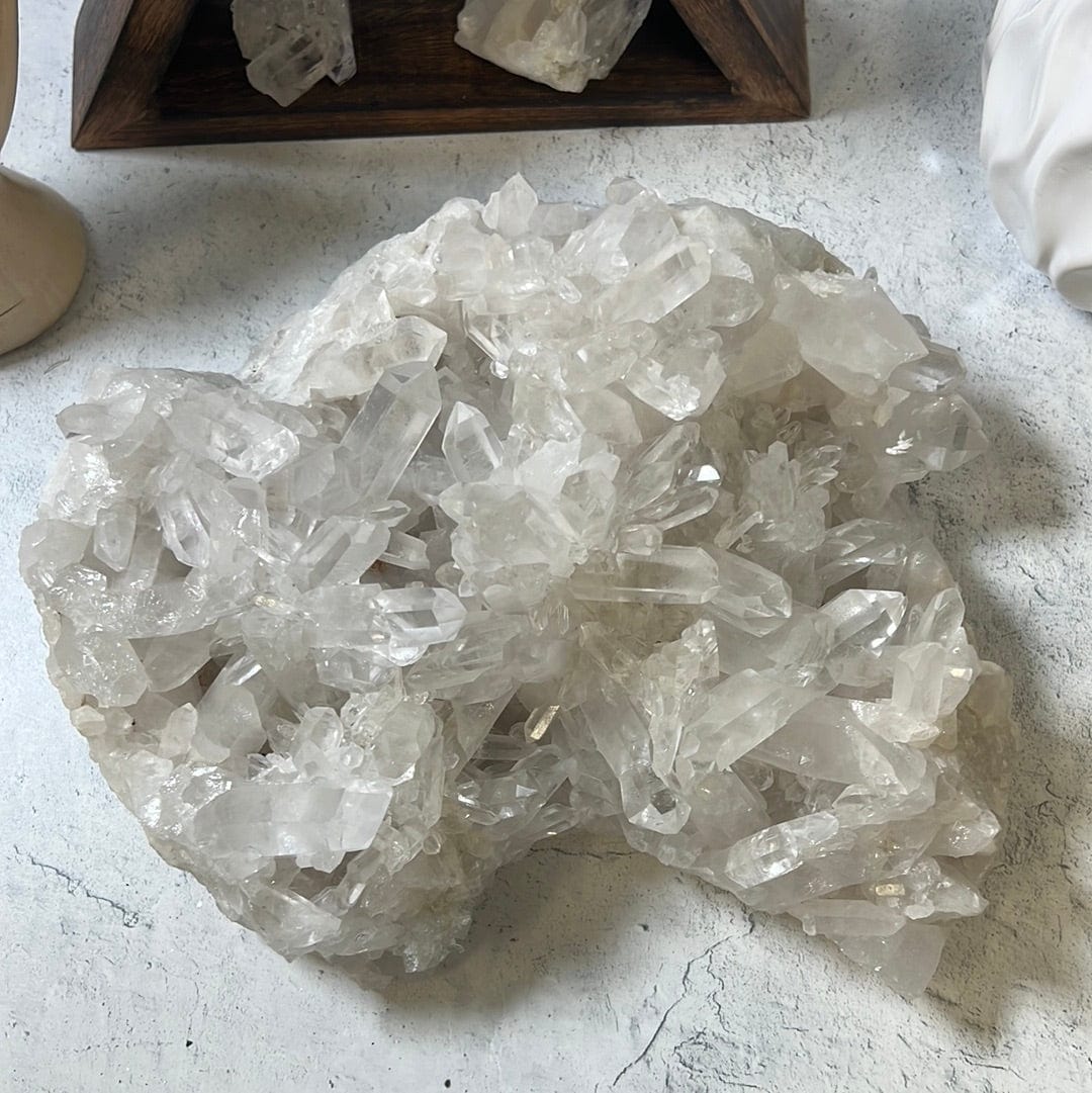 Large crystal cluster with points all over it on a cement background.