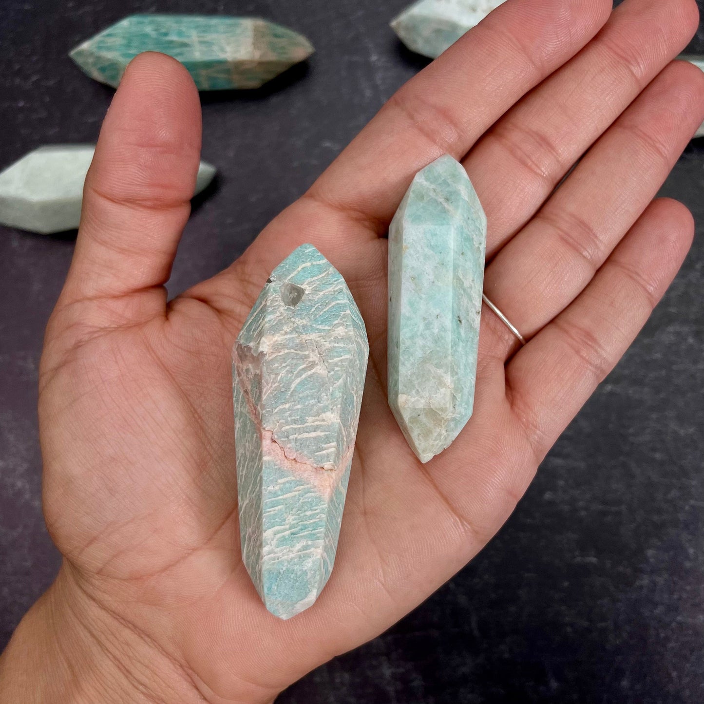 Two Amazonite Polished Double Terminated Points, in the weight range of 10g-50g, laying in palm of woman's hand.