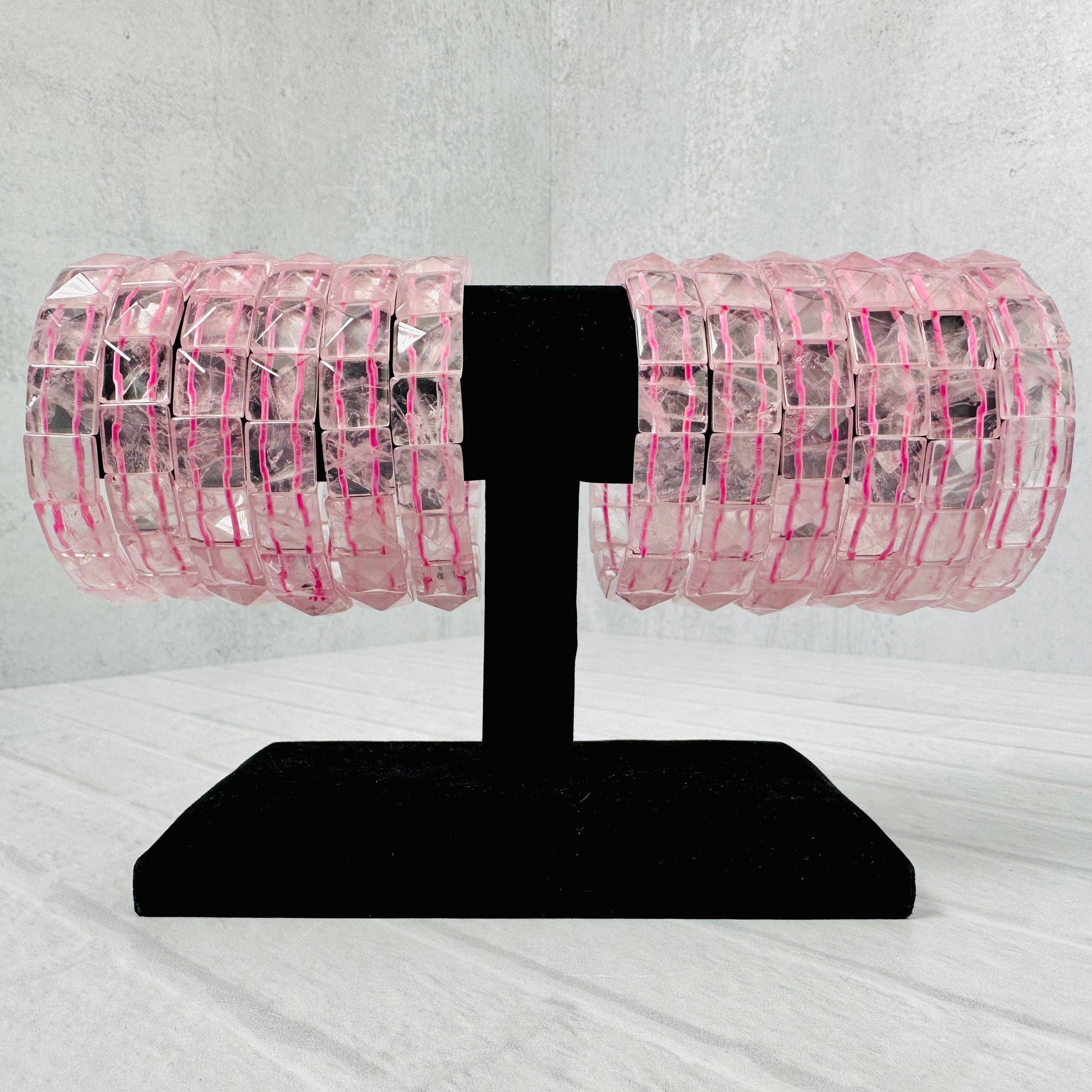 12 Rose Quartz Square Bead Bracelets on a black bracelet display.