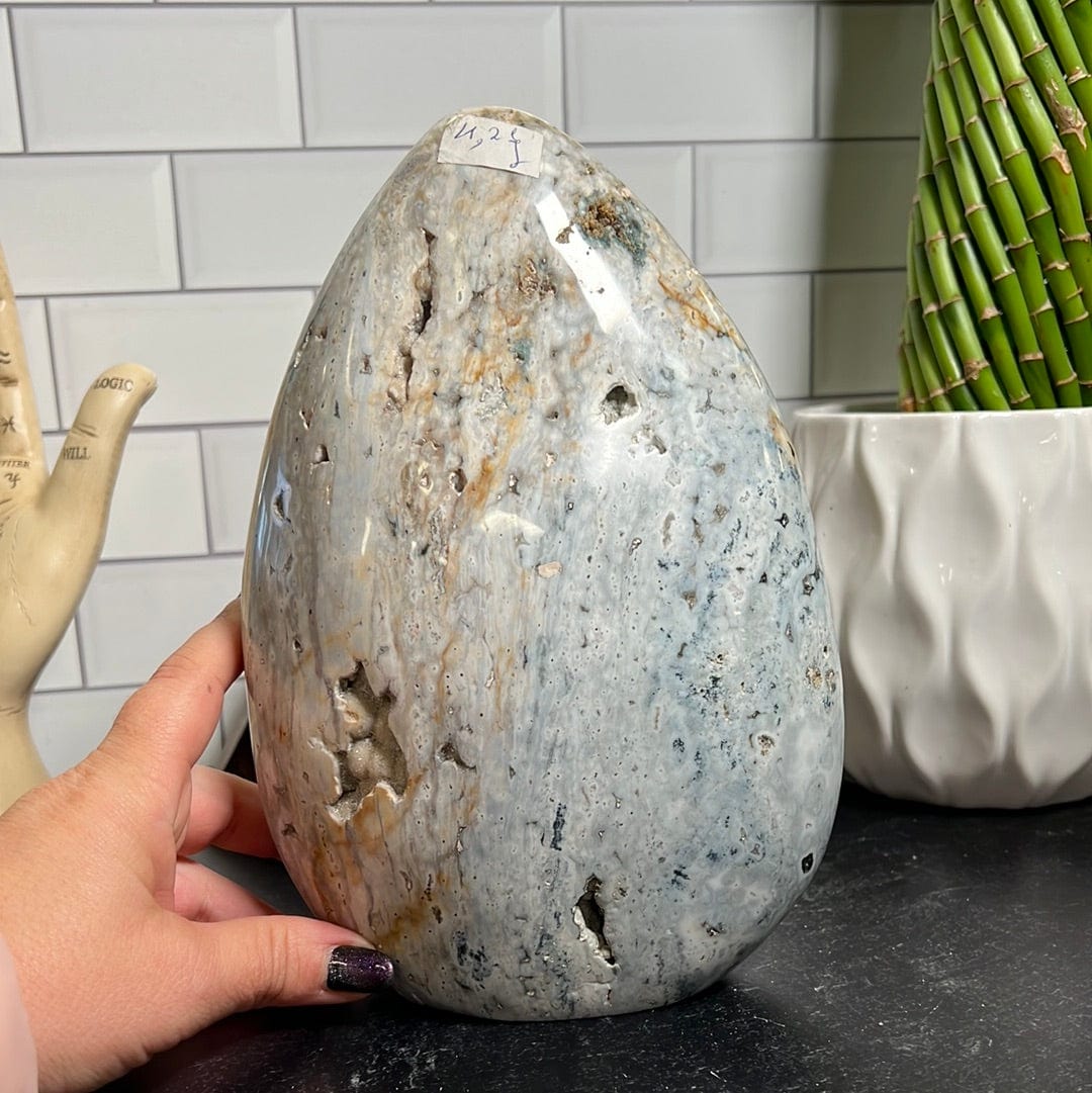Large ocean jasper cut base.  It is mostly white with shades of green, yellow and gray.  It has a few sparkly druzy pockets along the front.