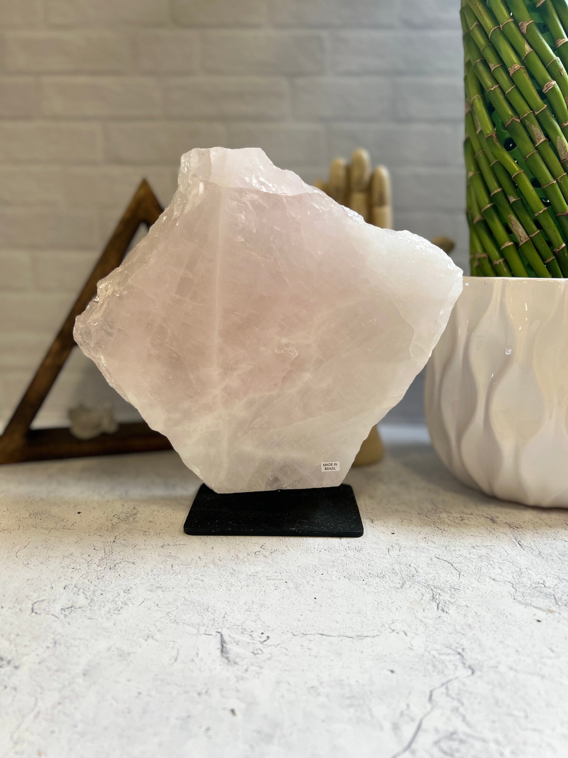 Rose Quartz large slab on a black metal base on a cement background.