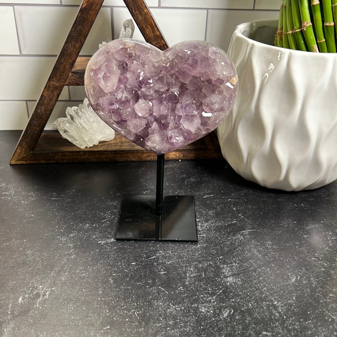 amethyst heart on a black metal stand on a black background.