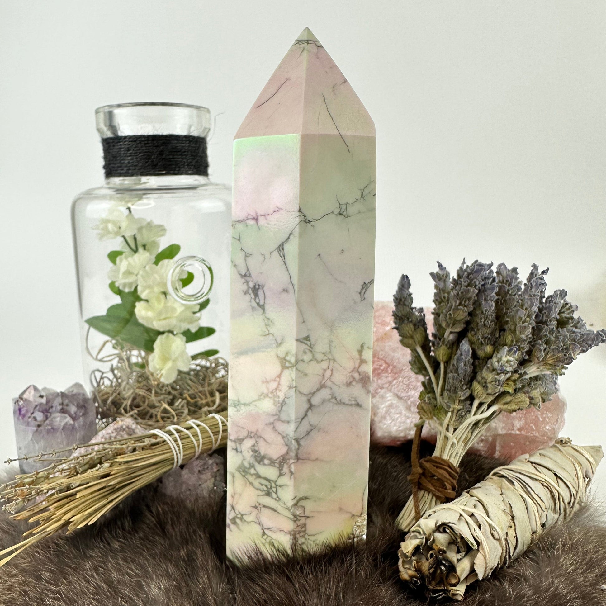 side view of white howlite aura tower with decorations in the background