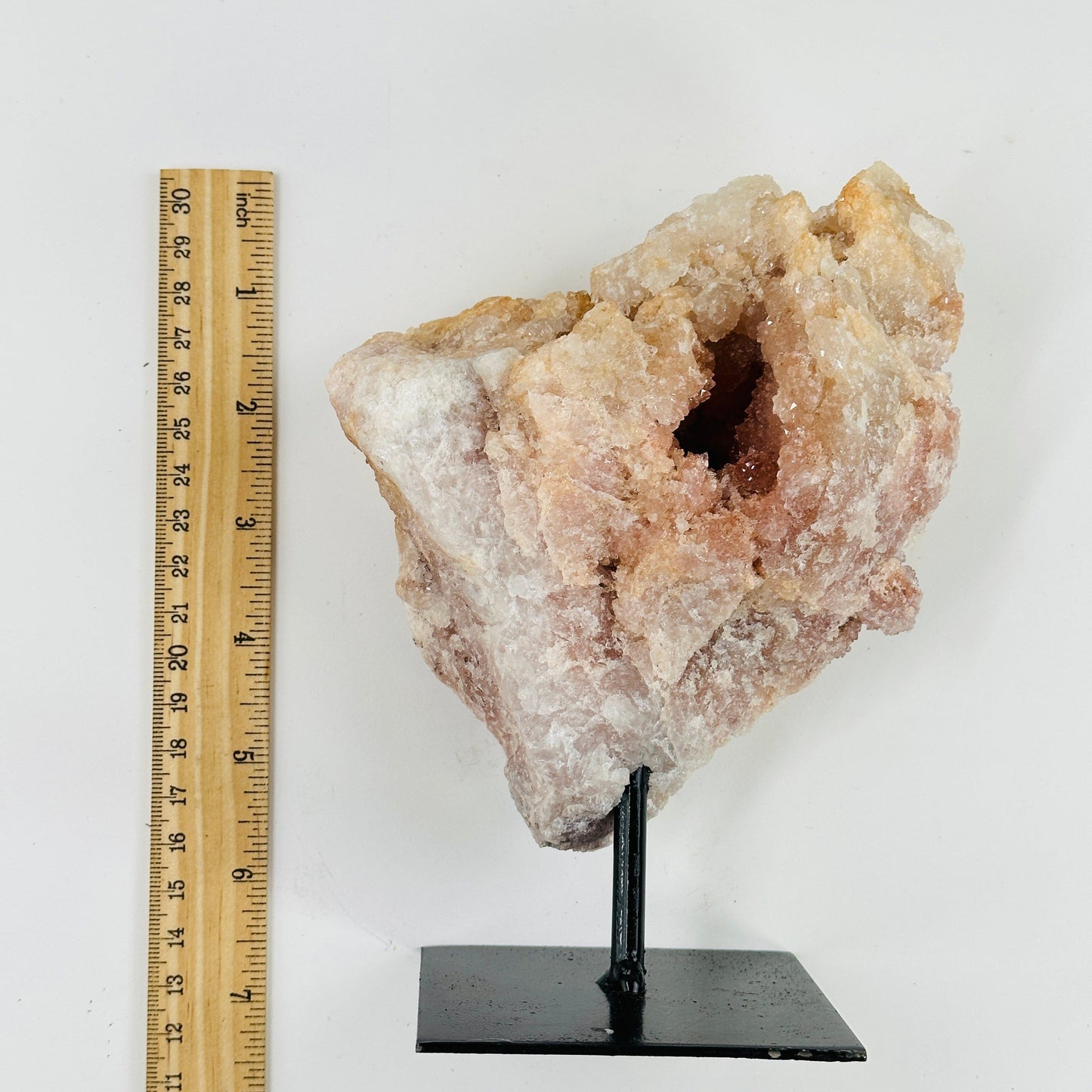 pink amethyst on metal stand next to a ruler for size reference