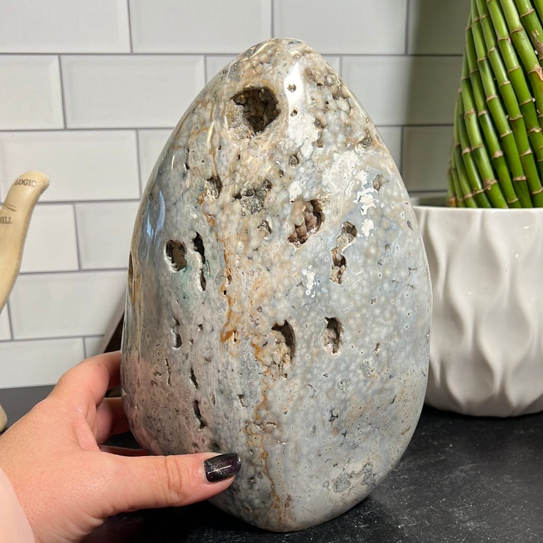 Large ocean jasper cut base.  It is mostly white with shades of green, yellow and gray.  It has a few sparkly druzy pockets along the front.