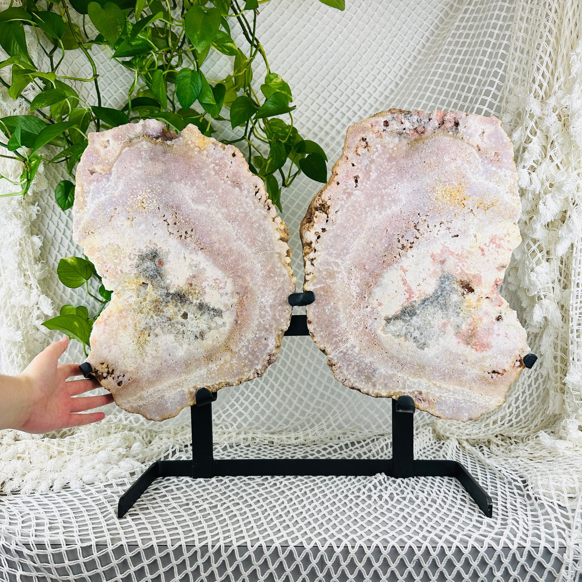 hand next to Pink amethyst double wings with decorations in the background