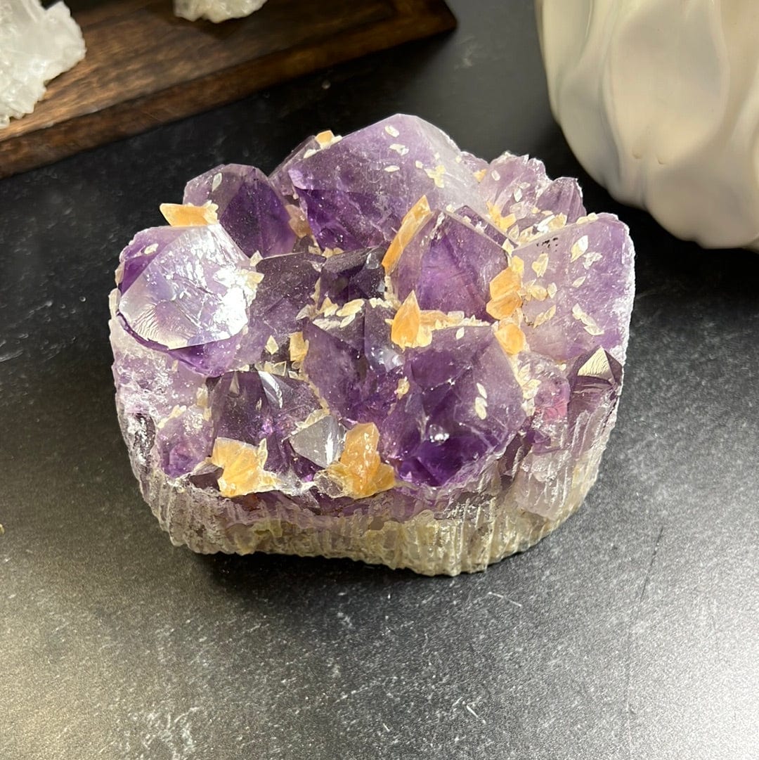 Amethyst cluster with orange calcite speckled throughout on a black background.