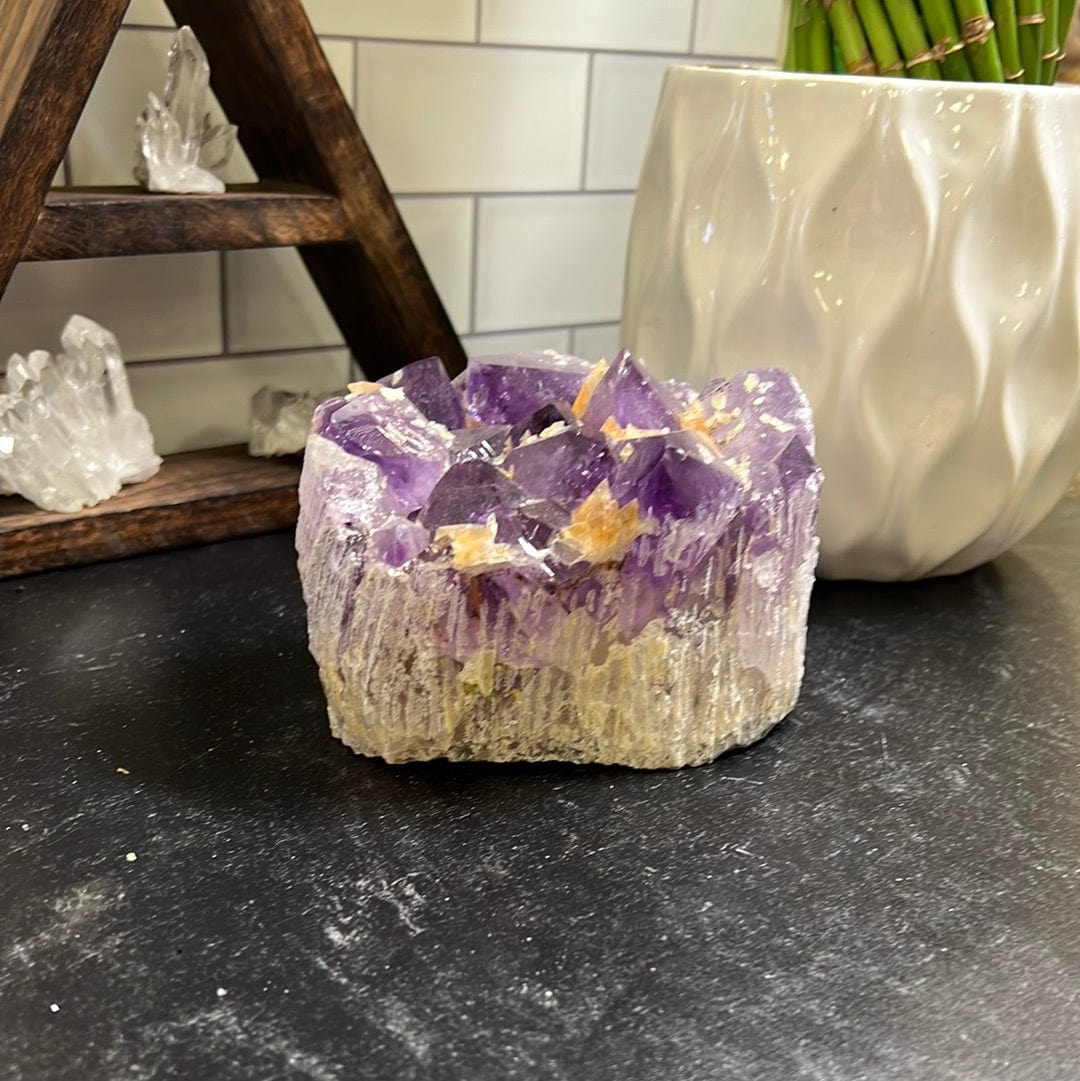 Amethyst cluster with orange calcite speckled throughout on a black background.
