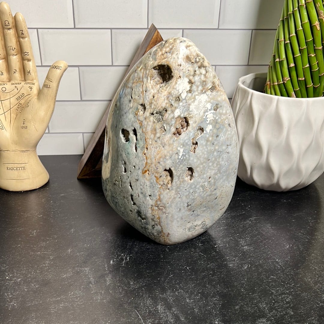 Large ocean jasper cut base.  It is mostly white with shades of green, yellow and gray.  It has a few sparkly druzy pockets along the front.