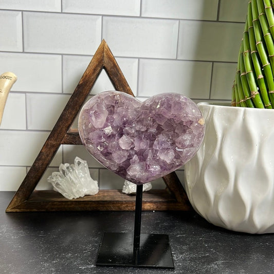 amethyst heart on a black metal stand on a black background.