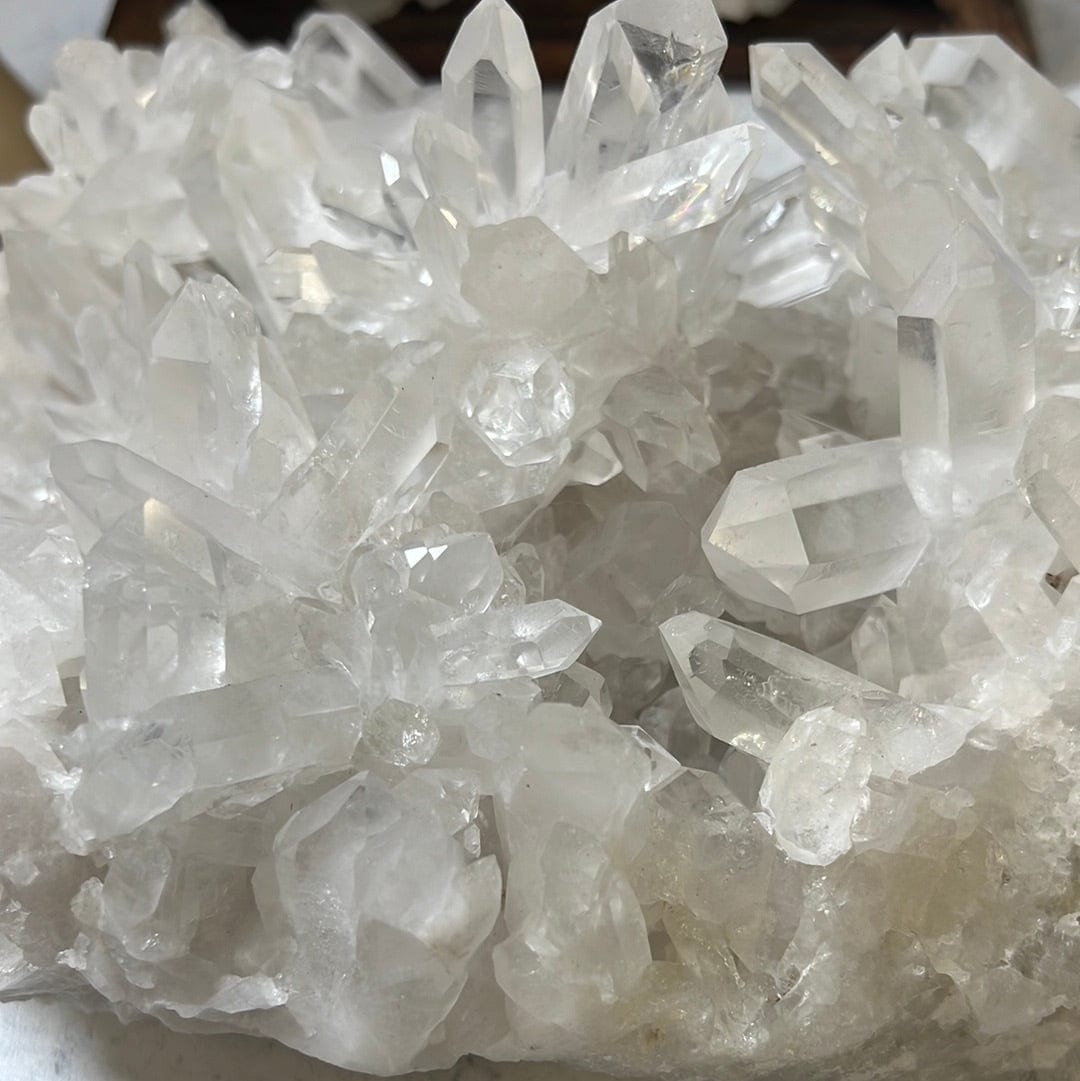 close up of Large crystal cluster with points all over it on a cement background.