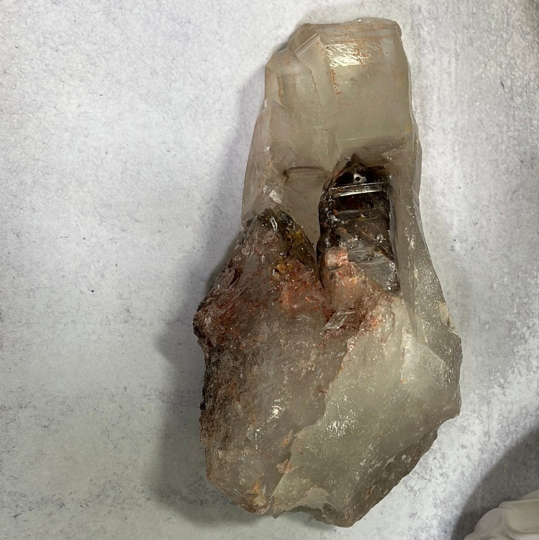 large smokey Quartz cluster on a cement background.