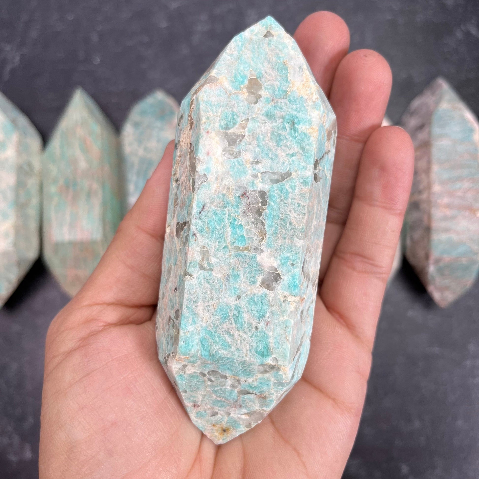 Amazonite Polished Double Terminated Point, in the weight range of 200g-250g, laying in palm of woman's hand.