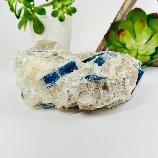 blue kyanite on matrix with decorations in the background