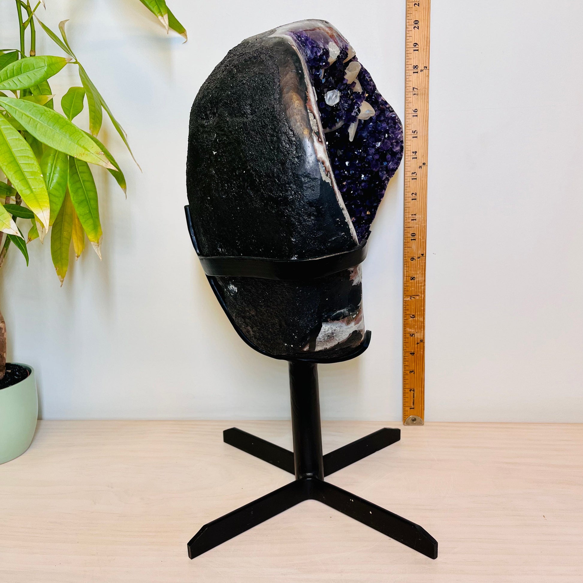 Left side view of Large Dark Purple Amethyst and Calcite Geode on Metal Stand next to a yard stick for size reference.