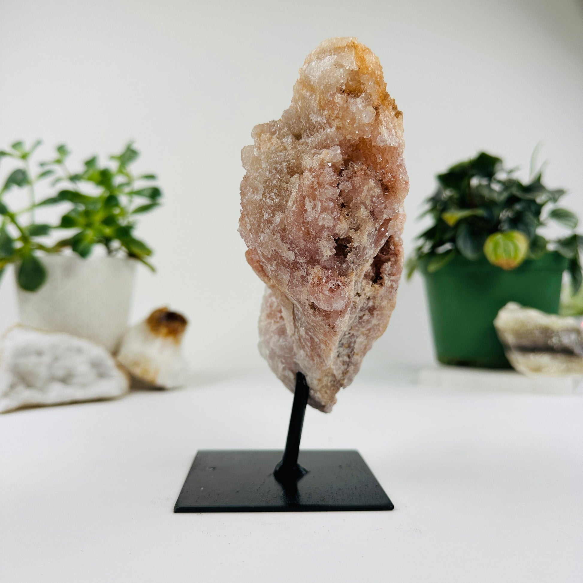 side view of Pink amethyst on metal stand with decorations in the background