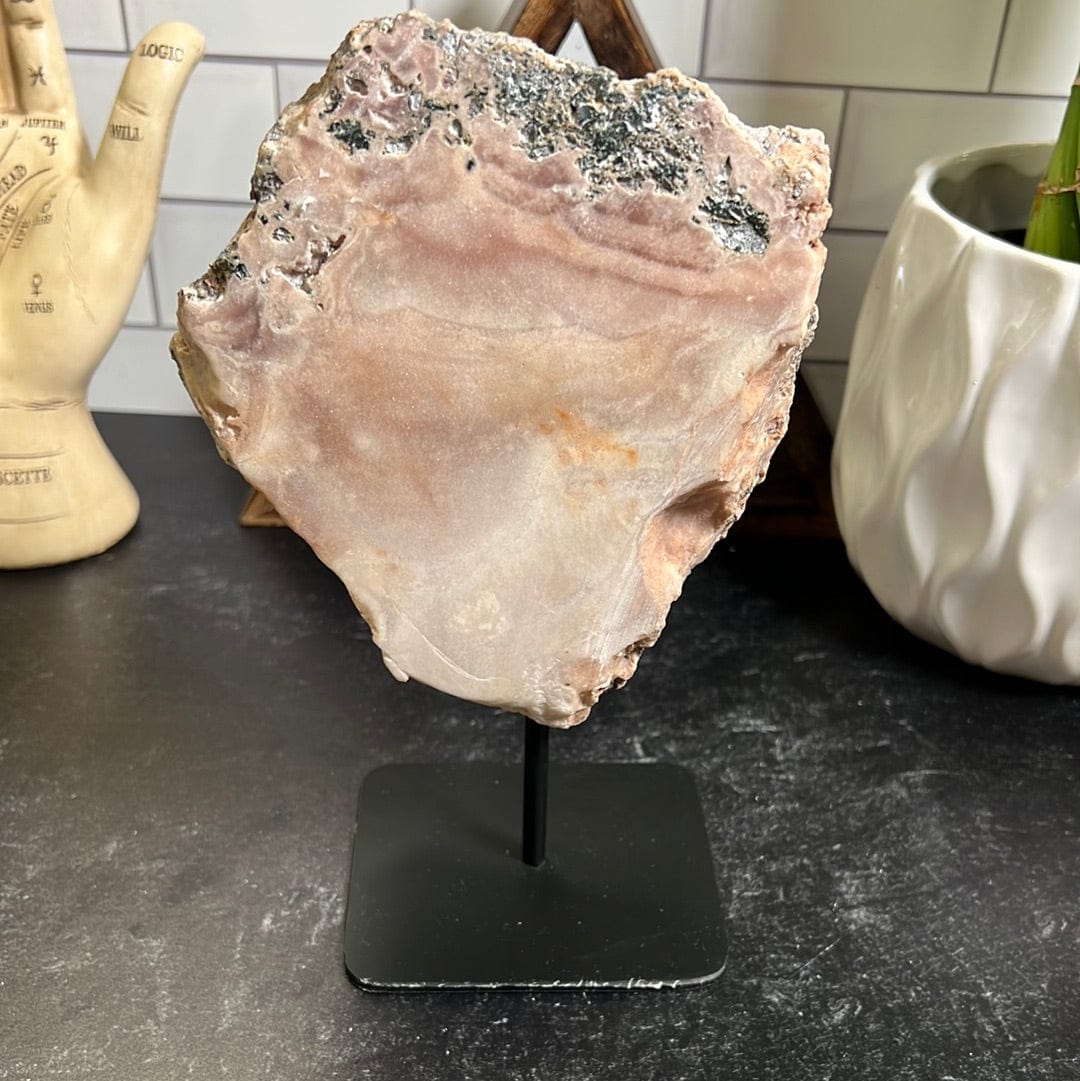 Pink amethyst slab on a black metal stand.