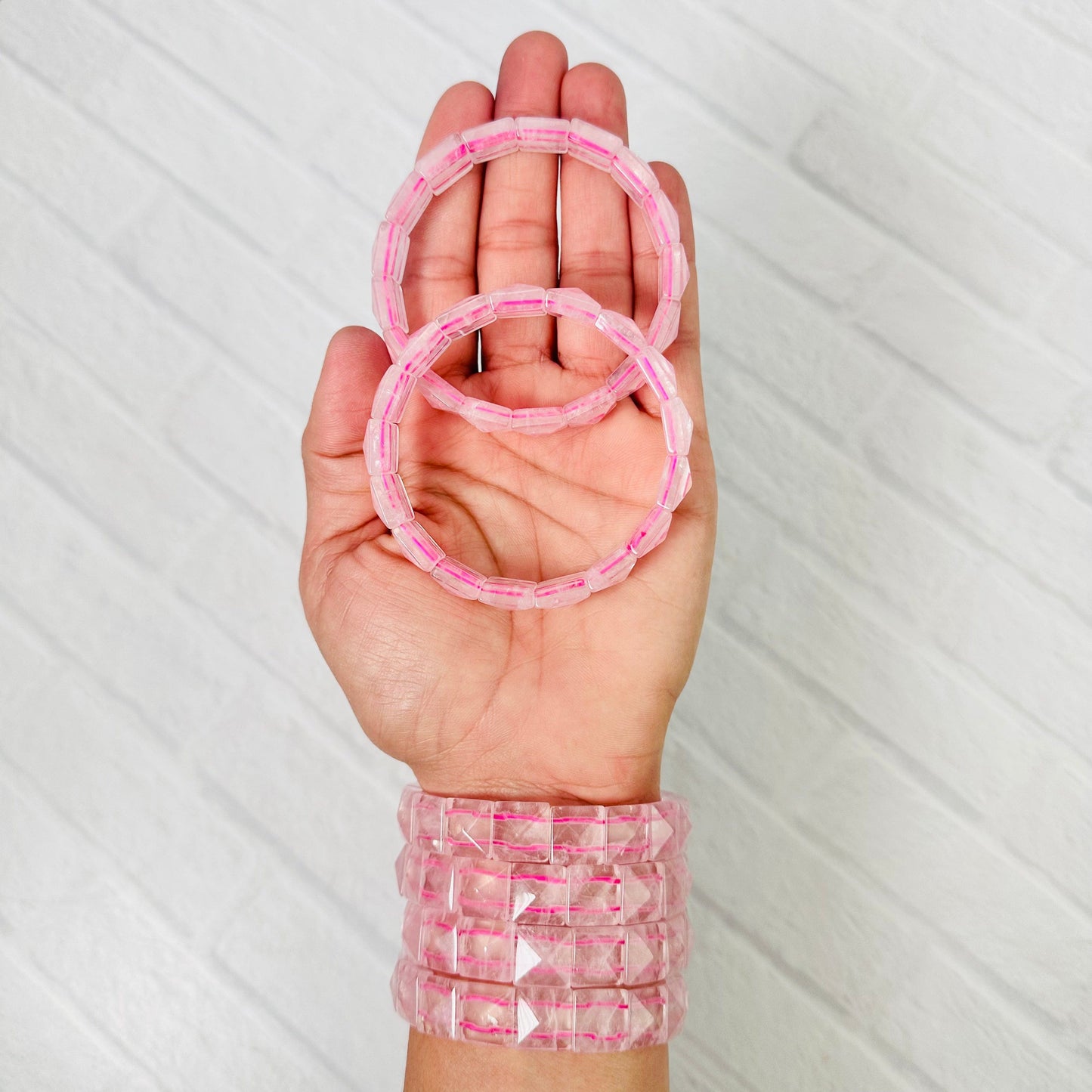 6 Rose Quartz Square Bead Bracelets displayed, 2 in palm of hand and 4 around wrist.