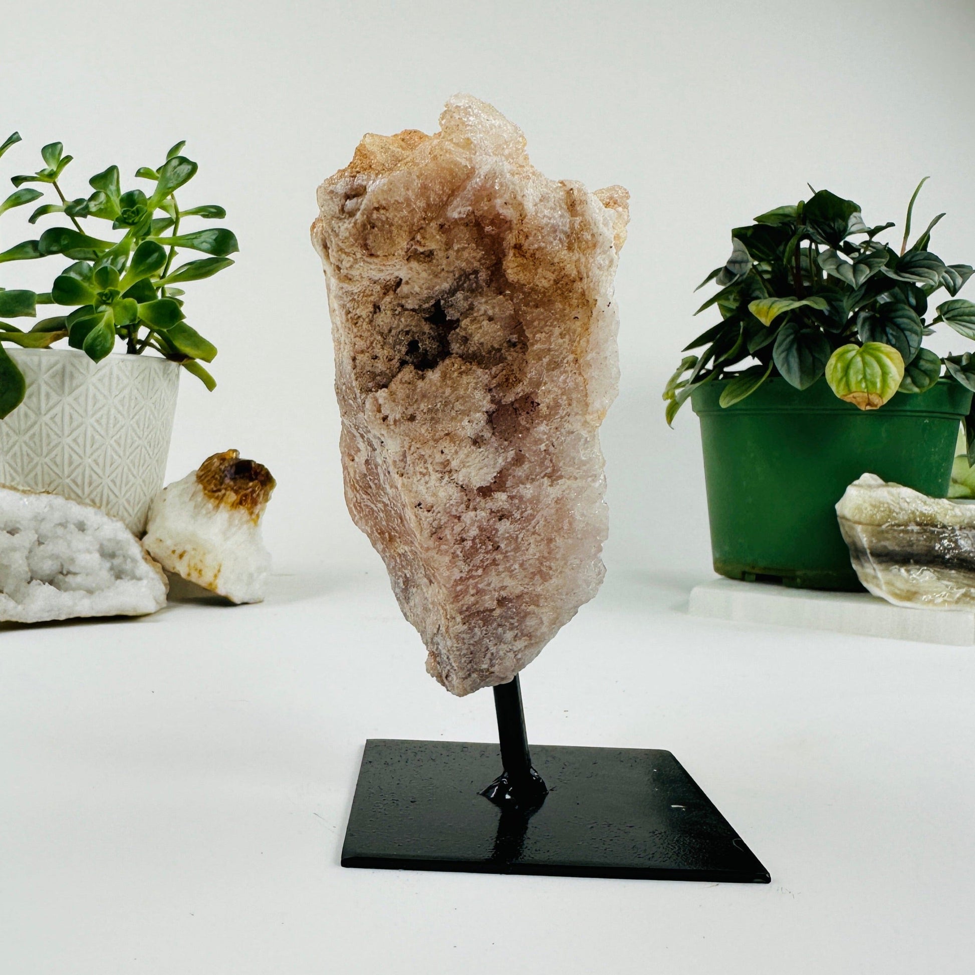 side view of Pink amethyst on metal stand with decorations in the background