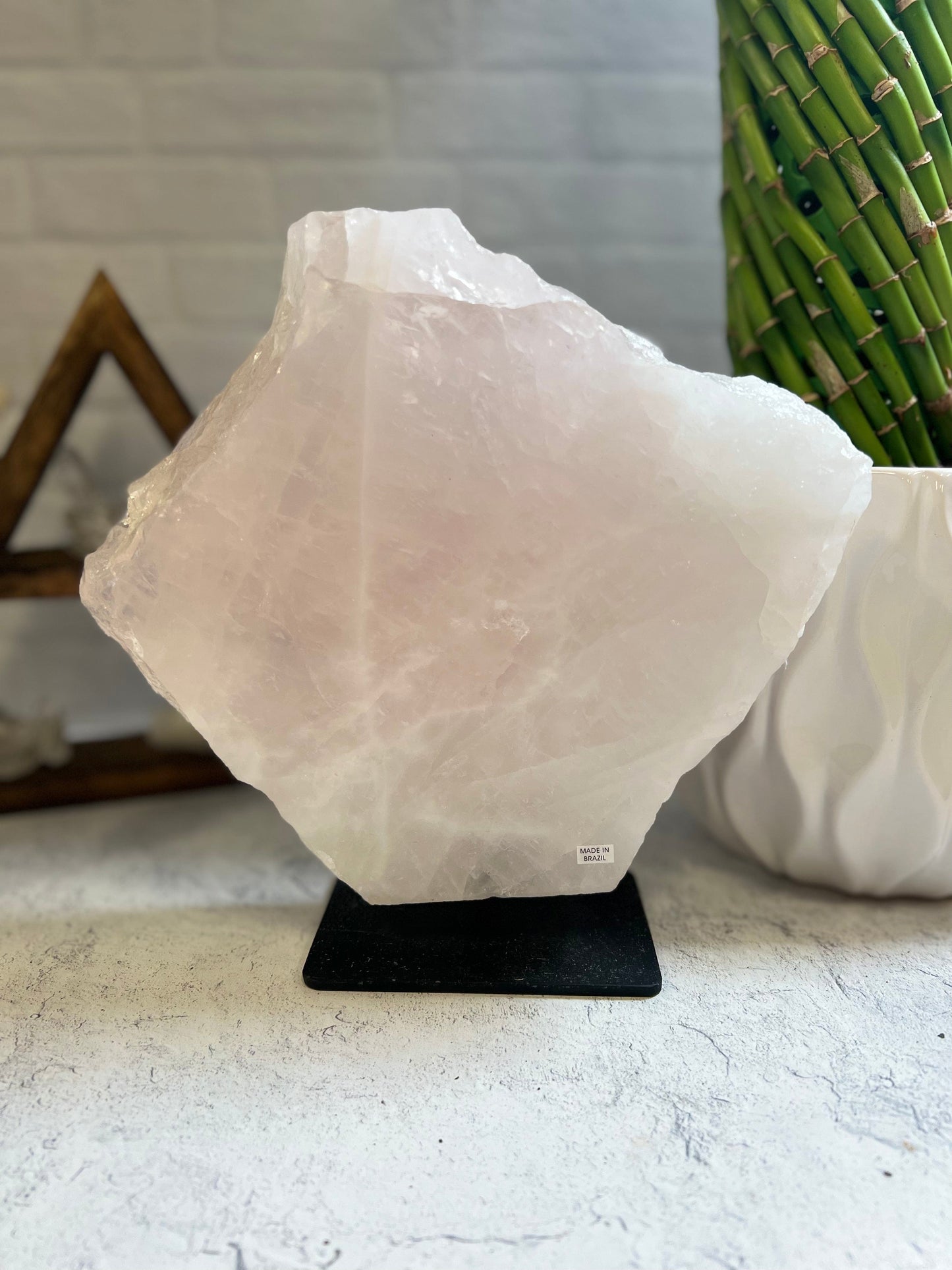 Rose Quartz large slab on a black metal base on a cement background.