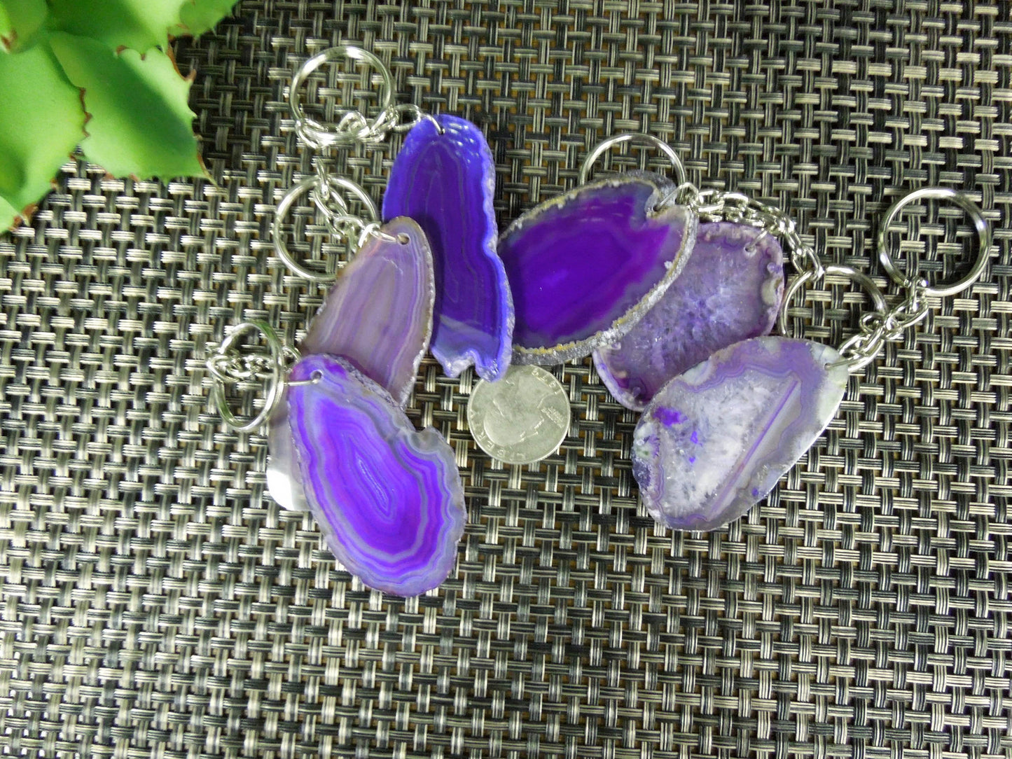 Multiple purple agate keychains next to a quarter for size reference.