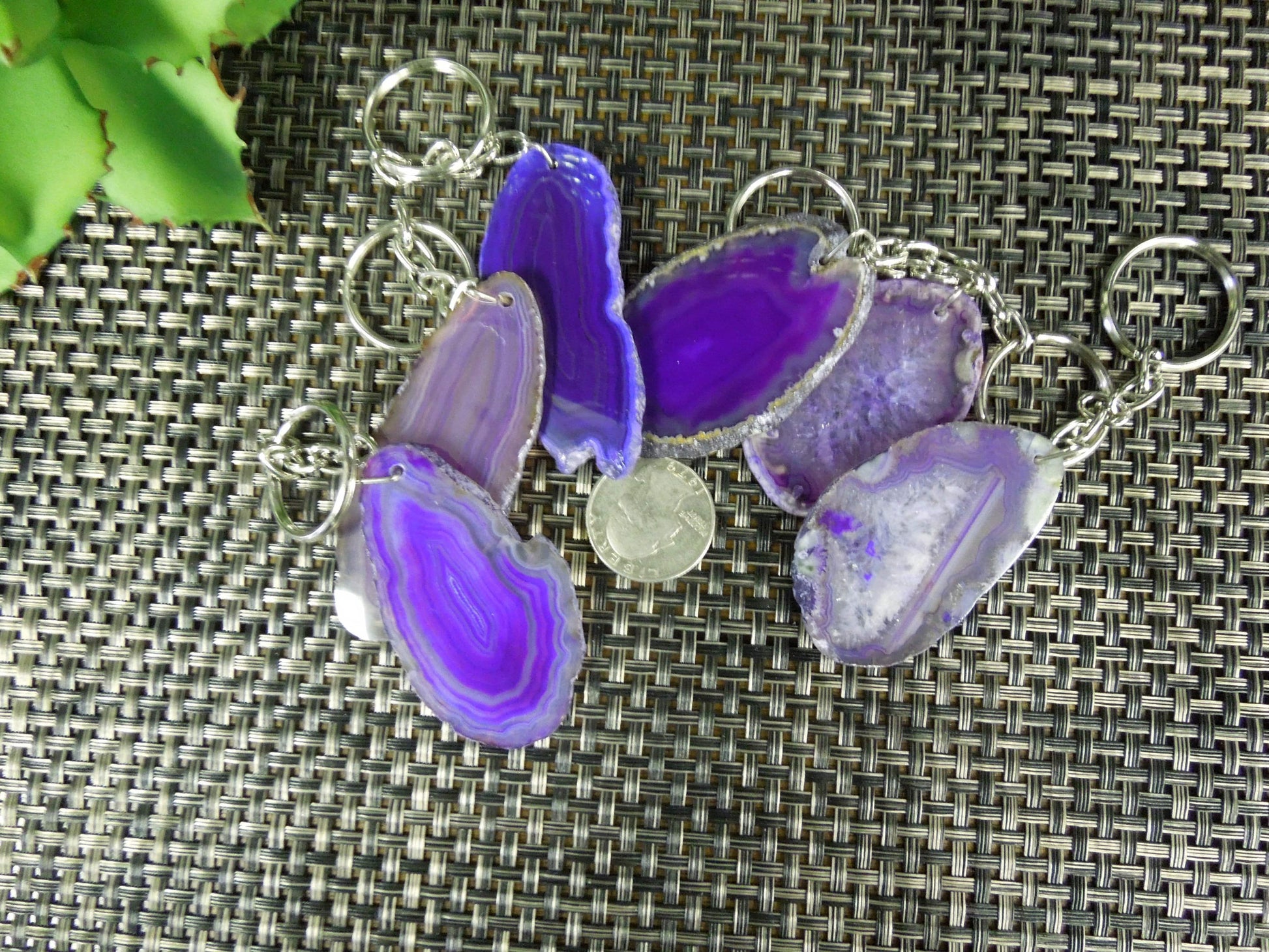 Multiple purple agate keychains next to a quarter for size reference.