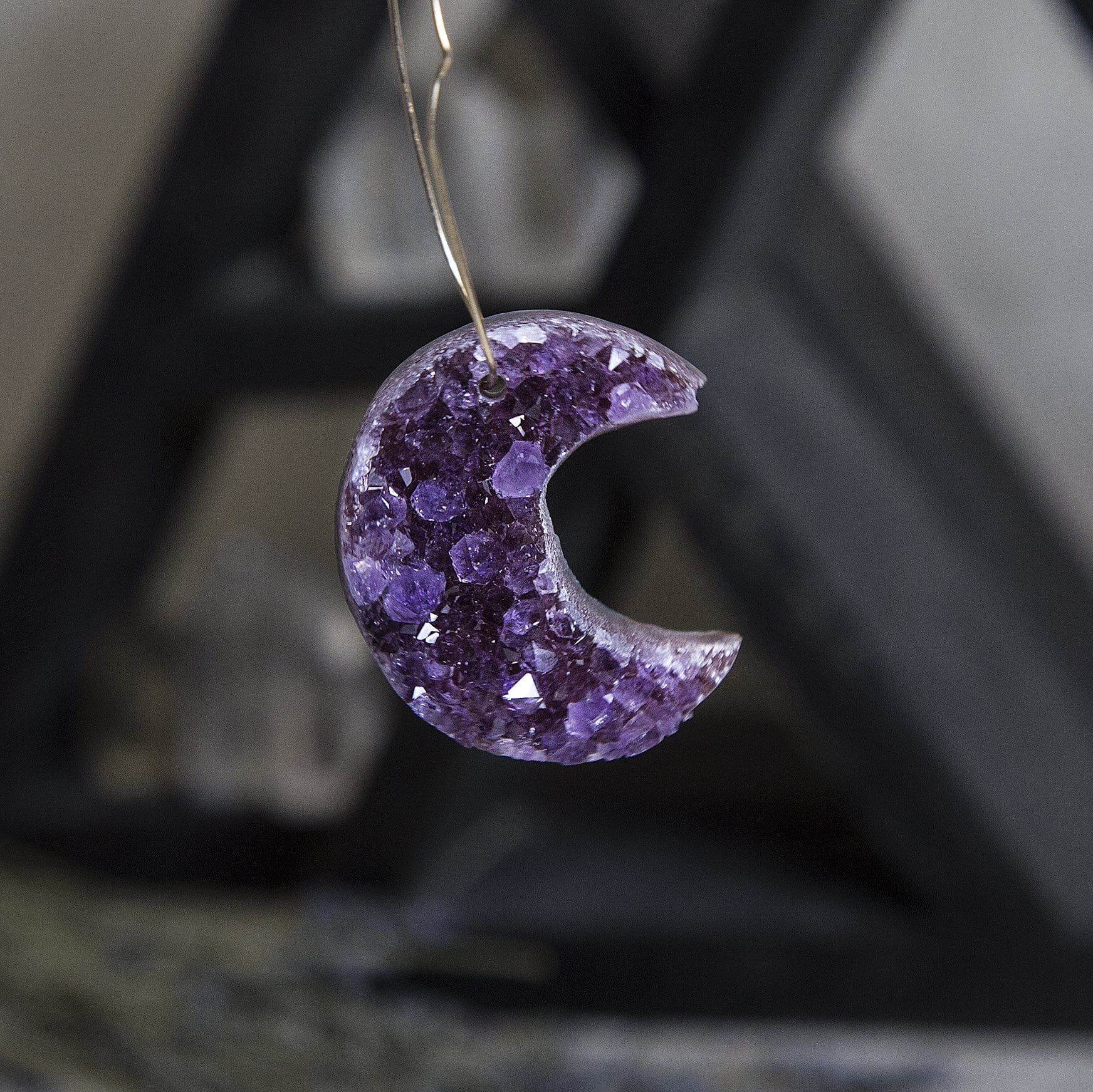 One amethyst moon handing from a wire to show the drill hole